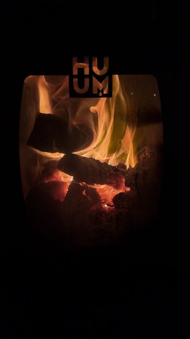 Flames and glowing coals inside the HUUM wood-fired stove