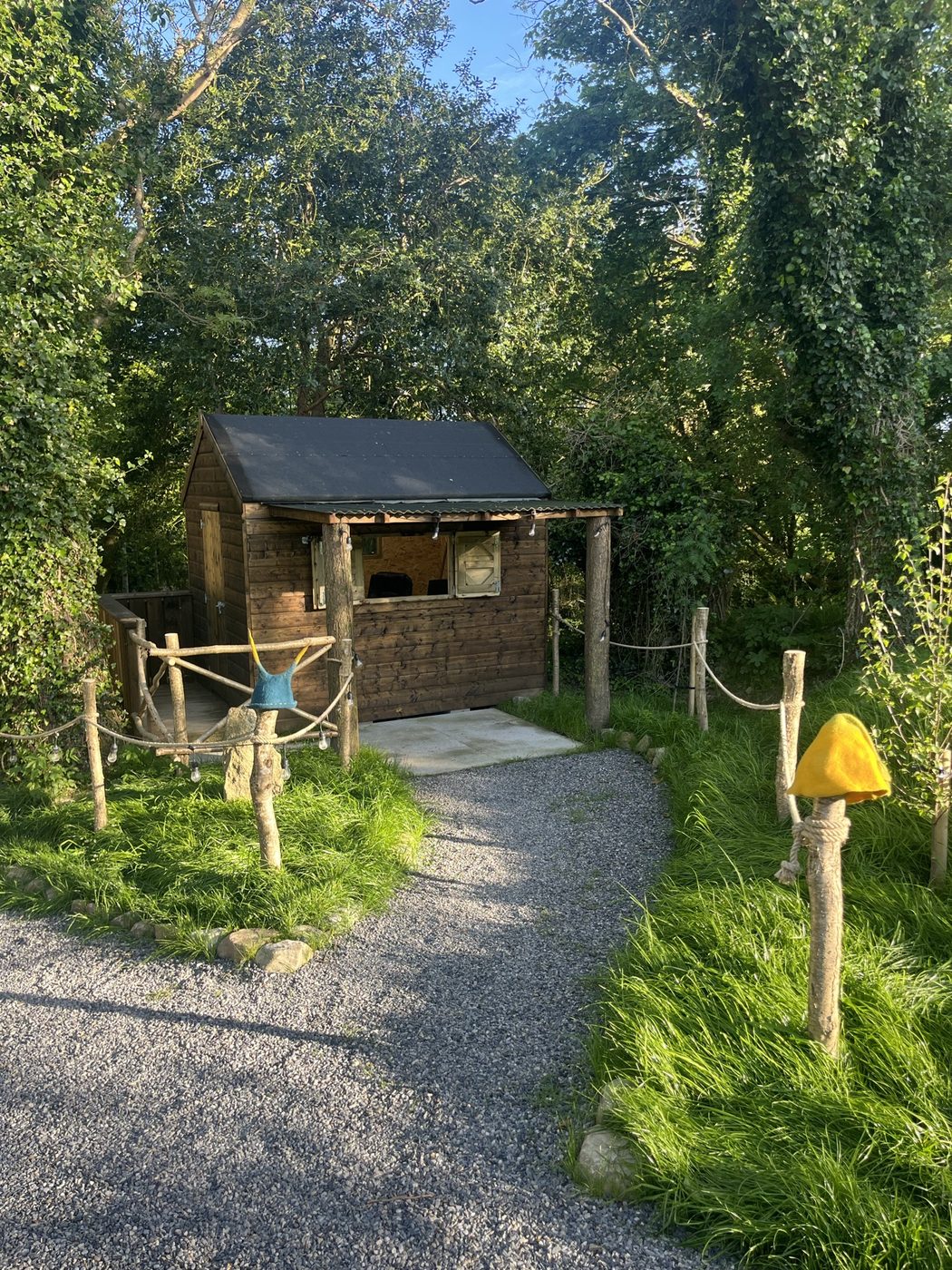 The gravel path winding past hazel posts and rope lighting on the way down to the sauna