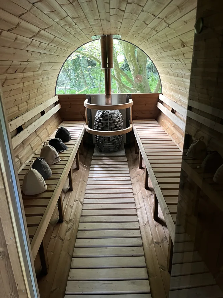 Looking down the cedar benches inside the barrel sauna toward the HUUM stove