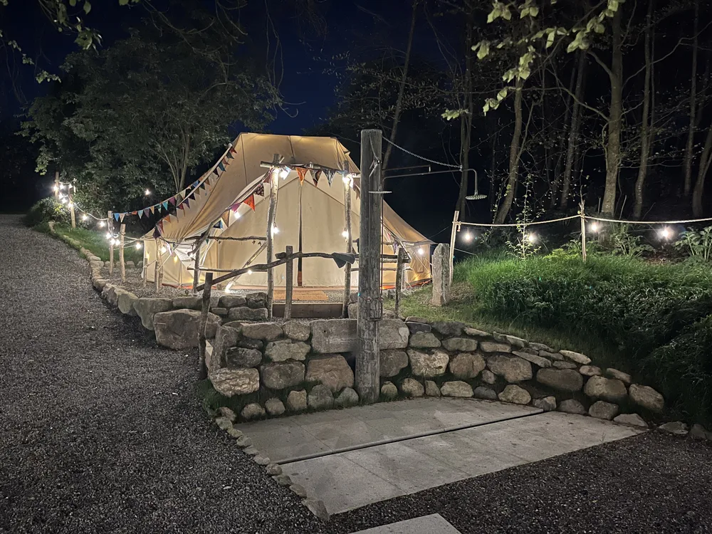 The changing yurt lit by string lights on a summer evening