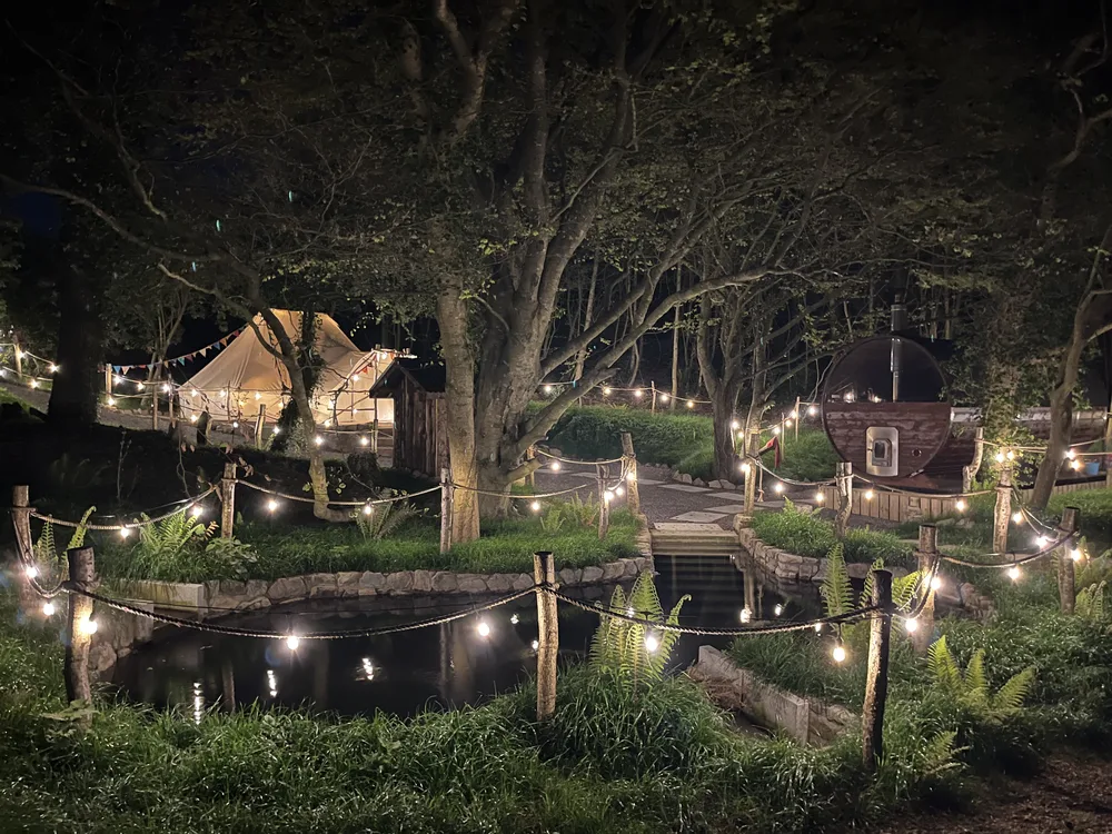 The clearing at night: yurt, sauna and plunge pool linked by lantern-lit paths